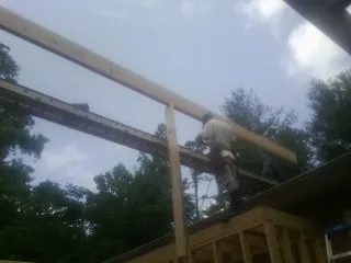 Carpenter setting a ridge beam over a new addition frame — Ice Dam Removal by Roofing Brothers in New Caney