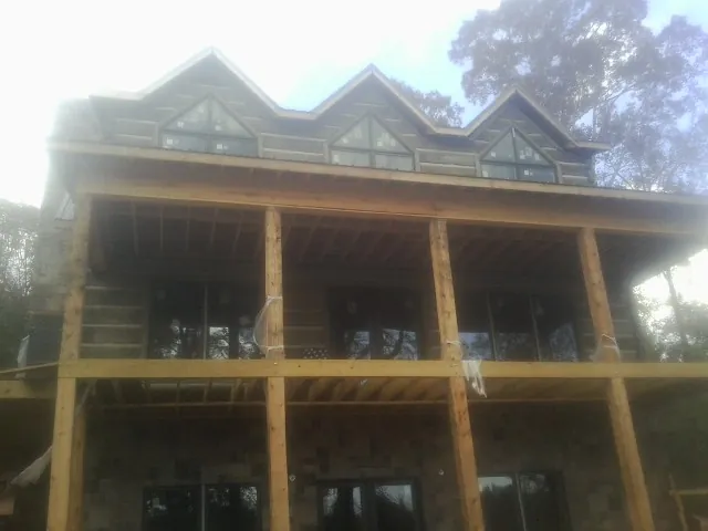 Dormers and porch framing on a large log home under construction — Roof Coating work by our crew in New Caney