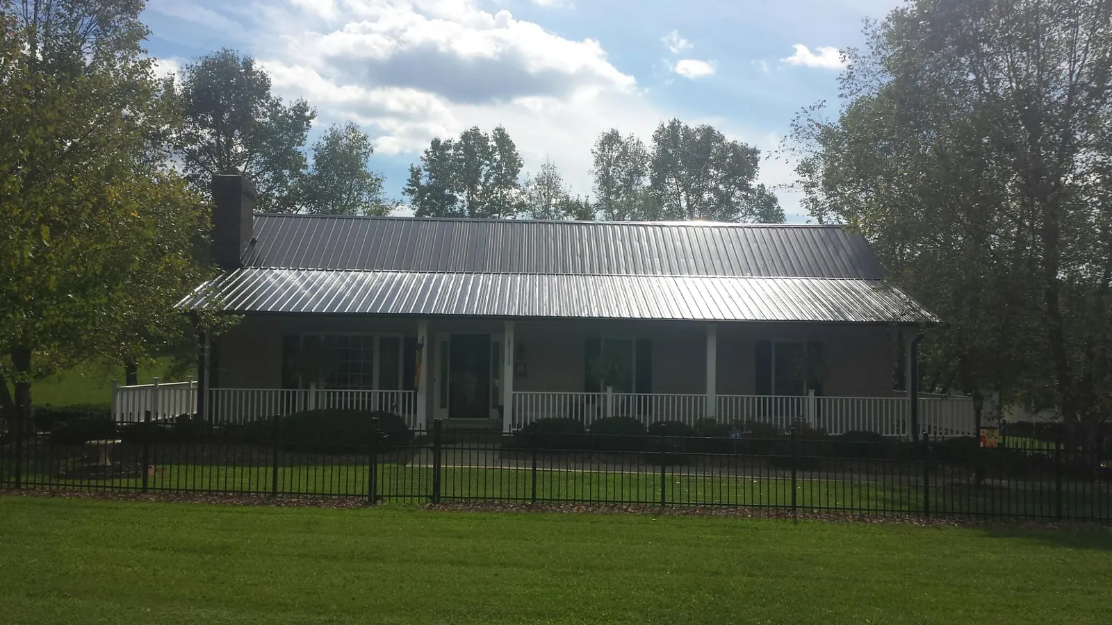 Gray metal roof on a brick ranch with a full width front porch — Gutter Guard Installation work by our crew in New Caney