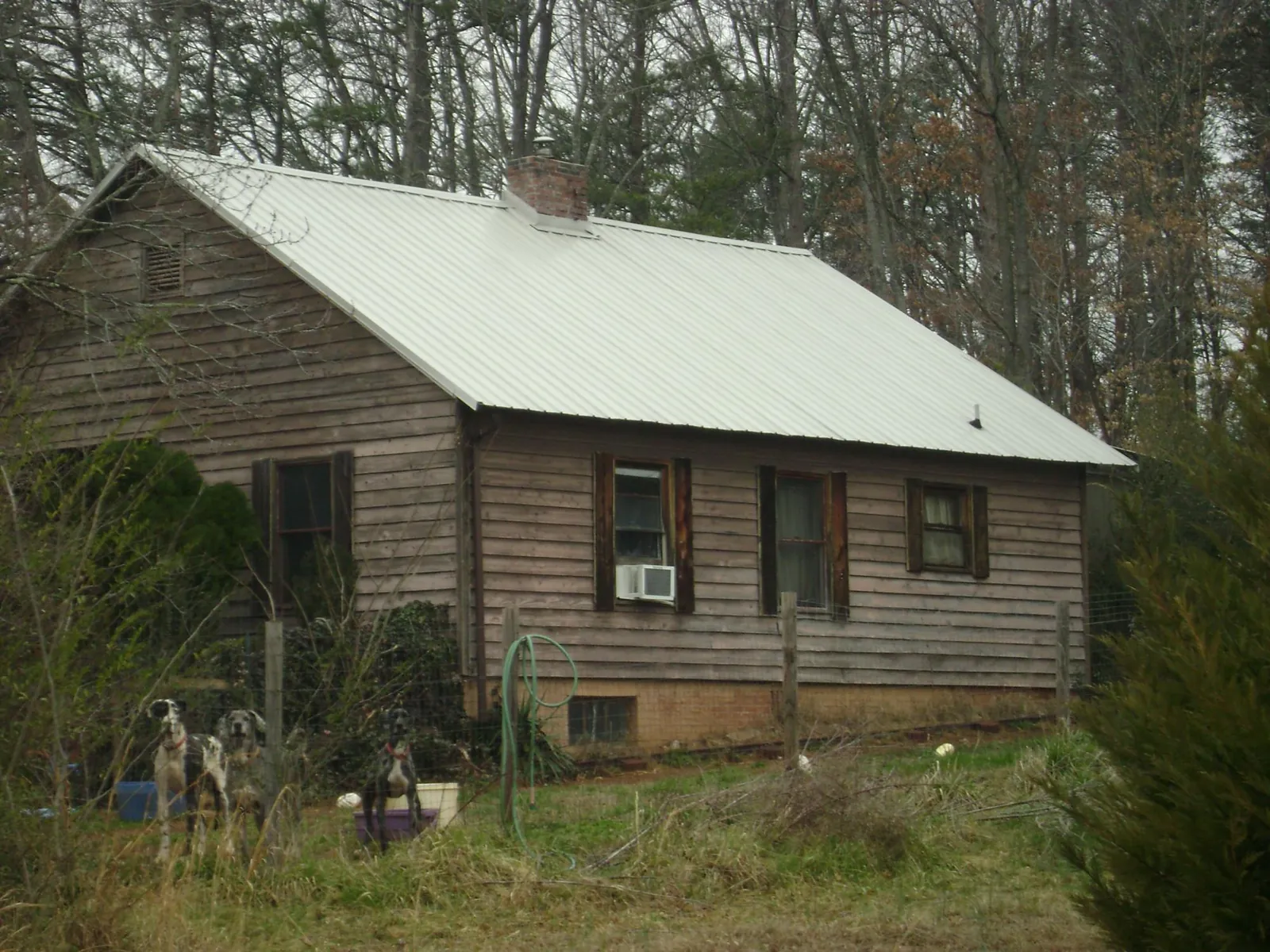 White metal roof on an old wood sided farmhouse, from a Metal Roof Installation job in New Caney