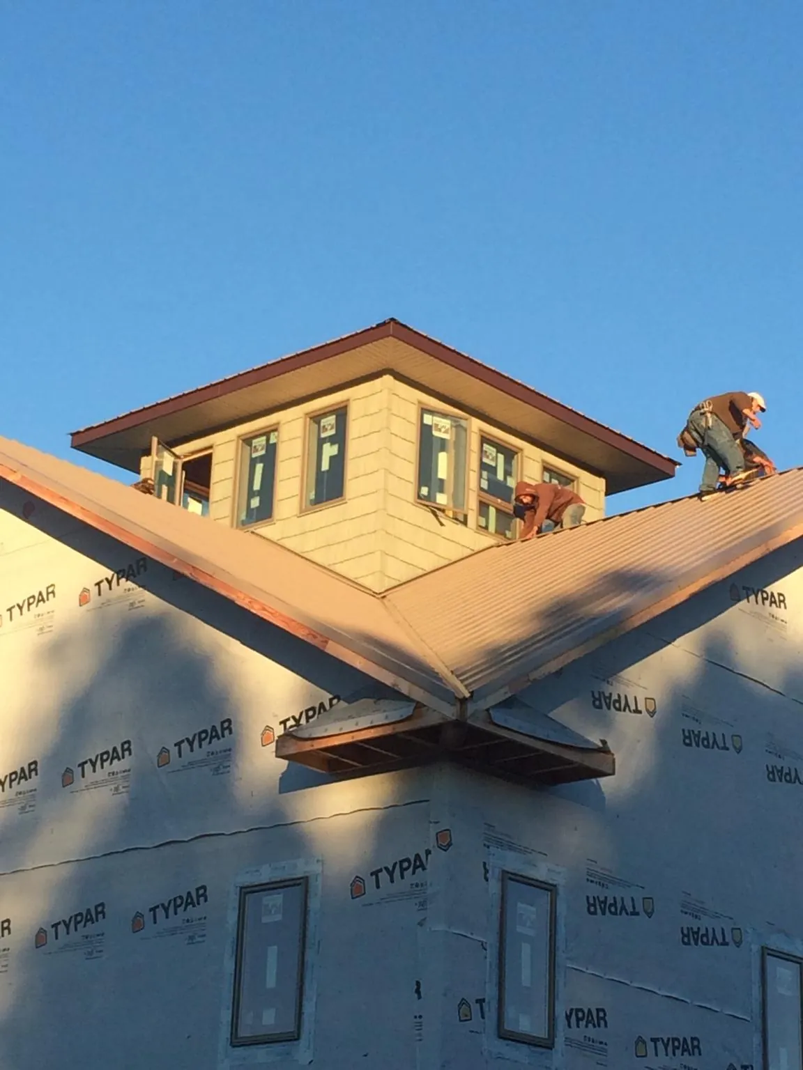 Roofers working around a rooftop cupola on a new metal roof at sunset — Roof Waterproofing in New Caney by Roofing Brothers